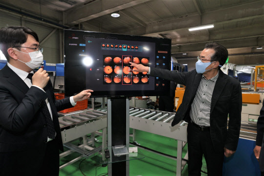 이성희(오른쪽) 농협중앙회장이 28일 제주 서귀포농협 APC를 방문해 인공지능 귤 선별기를 살펴보고 있다. <농협중앙회 제공>